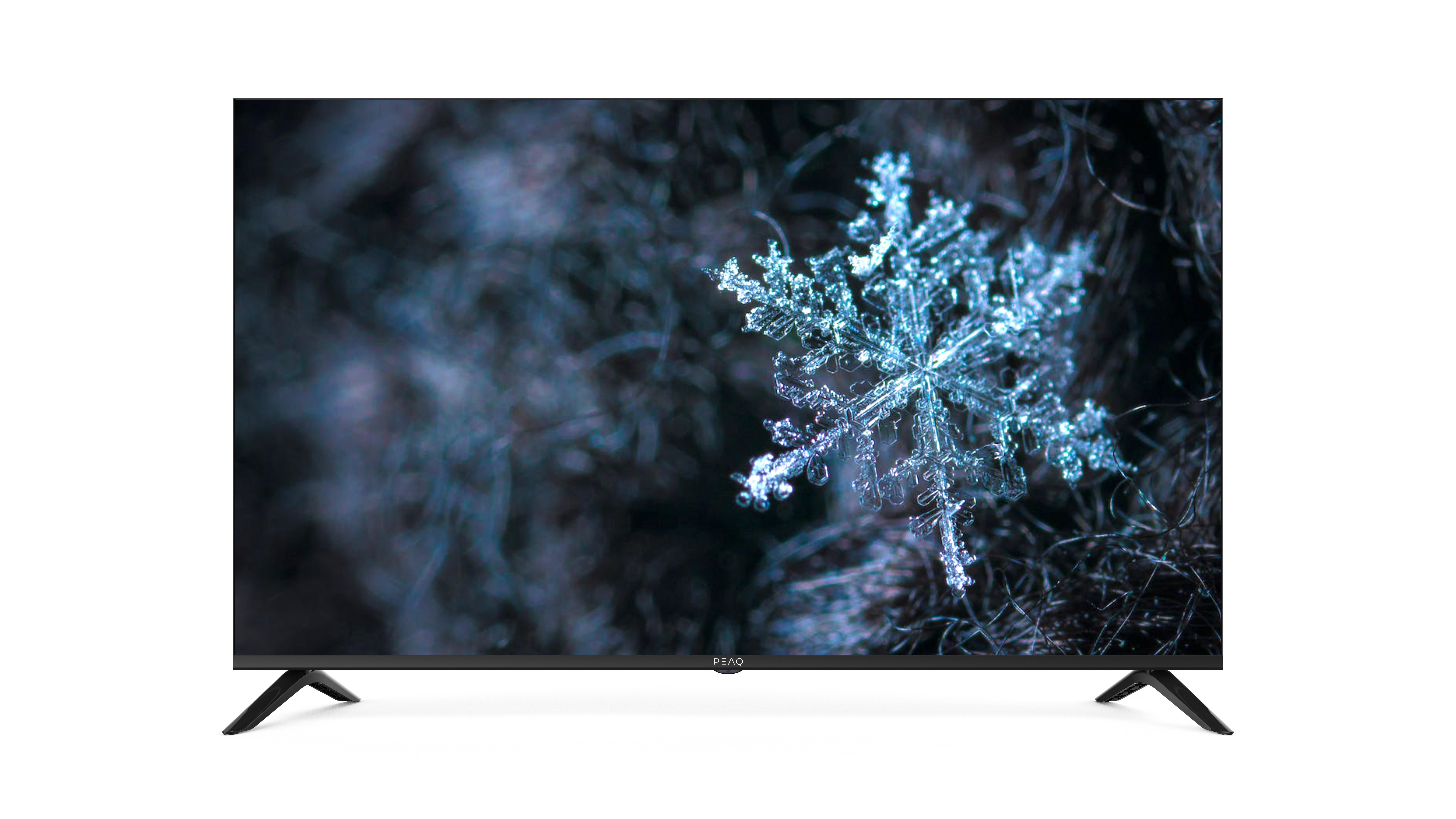 Der Fernseher zeigt eine Schneeflocken-Makroaufnahme vor unscharfem Hintergrund. Schwarzer Ständer.