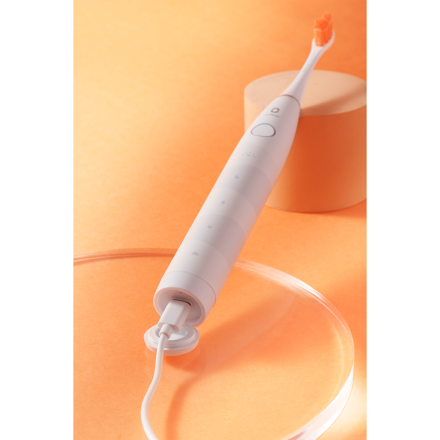 Uno spazzolino elettrico bianco con testina arancione e base di ricarica.