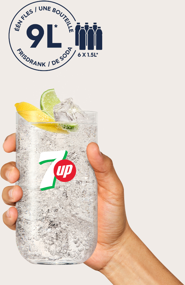 Hand holding a tall glass of 7-Up with ice, lemon, and lime, on a light background.