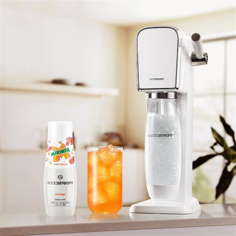 Machine SodaStream avec soda à l'orange, un verre avec de la glace et une bouteille de Mirinda.