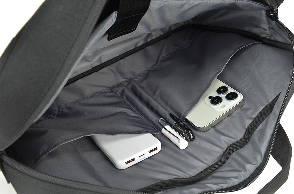 In einer schwarzen Laptoptasche mit Gegenständen: Powerbank, Stifte und Telefon.