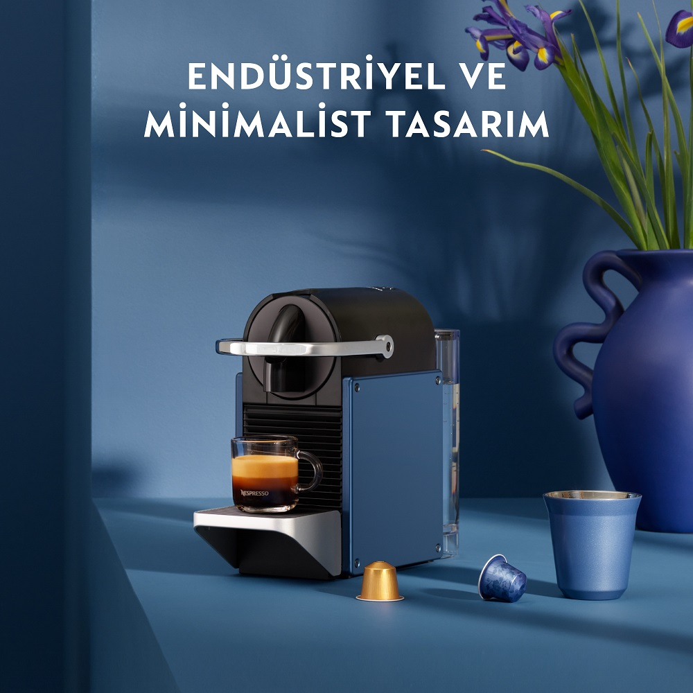 Bir Nespresso makinesi, bir kahve fincanı ve iki kapsül ile birlikte 'ENDÜSTRİYEL VE MİNİMAL TASARIM' kelimeleri.