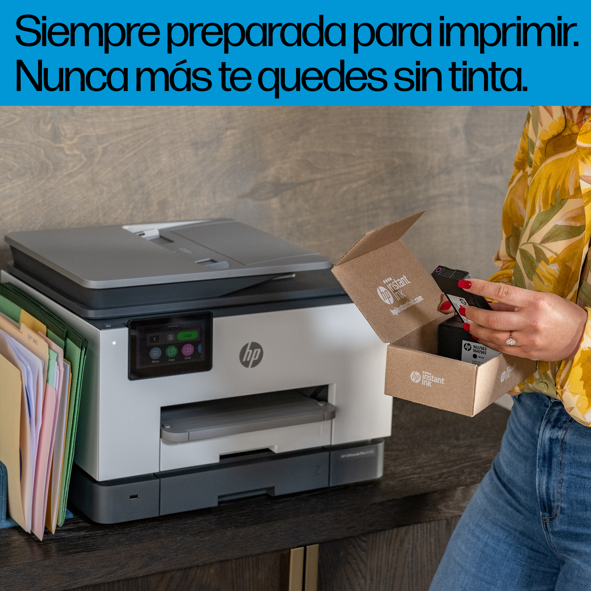 Mujer abriendo caja de tinta de impresora, impresora en el fondo.