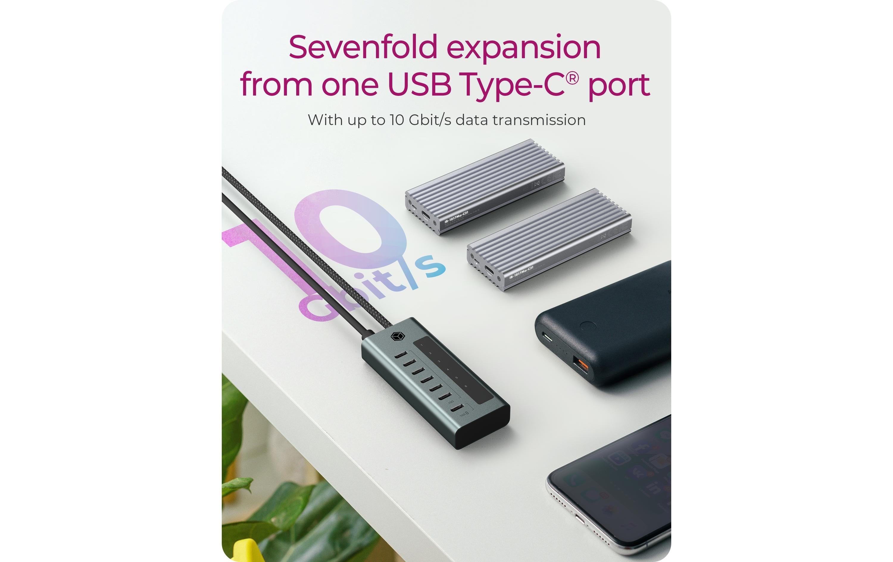 L'image présente un hub USB-C, des disques durs, un téléphone et une batterie externe sur une surface blanche.