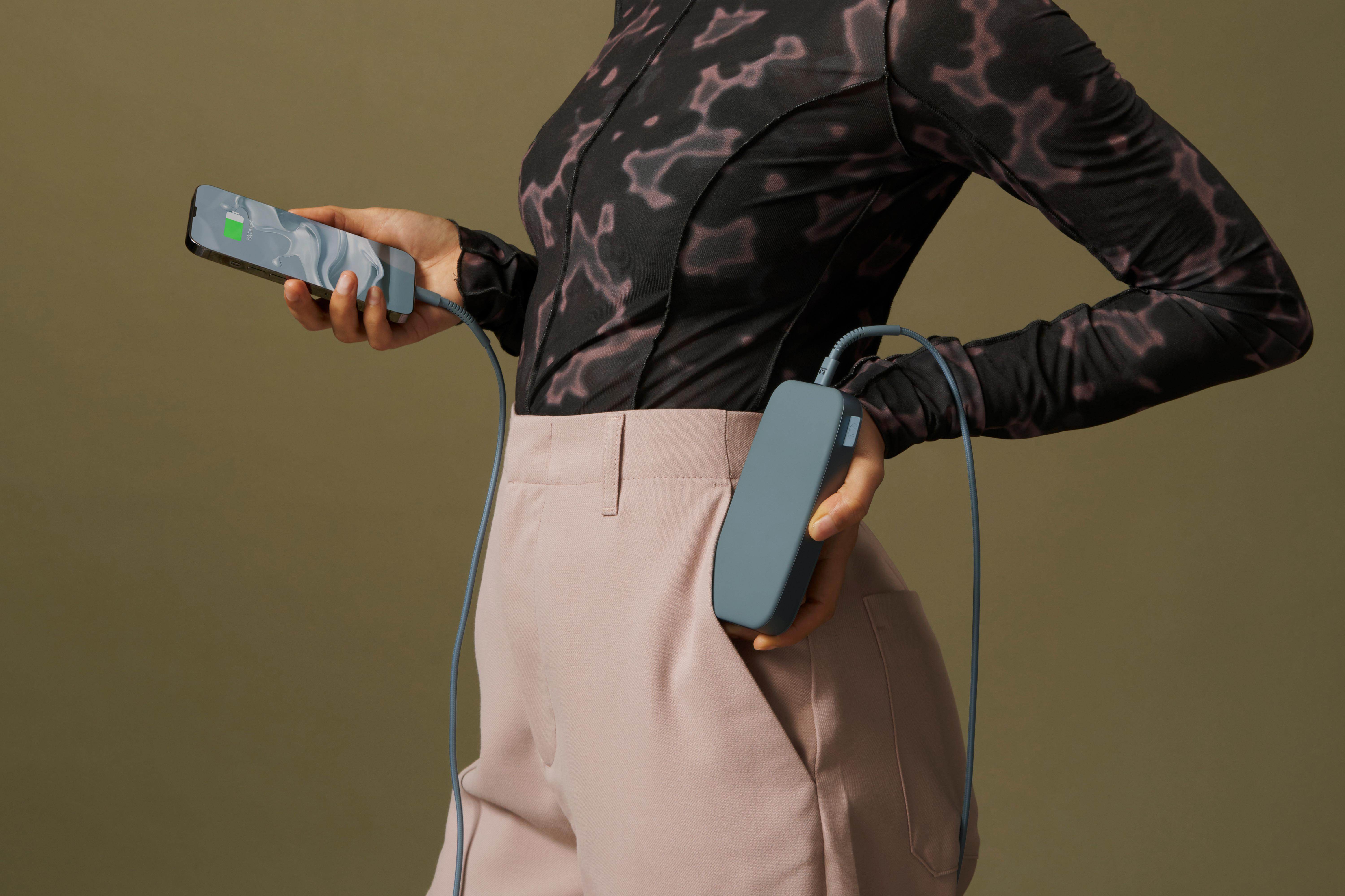Eine Person hält ein Telefon und eine Powerbank, die mit einem Ladekabel verbunden sind.