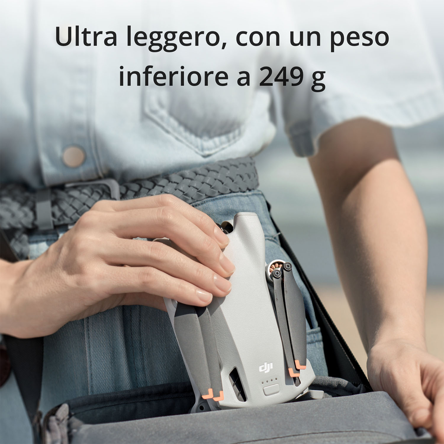 Una persona che tiene in mano un piccolo drone bianco. Il drone ha accenti arancioni.