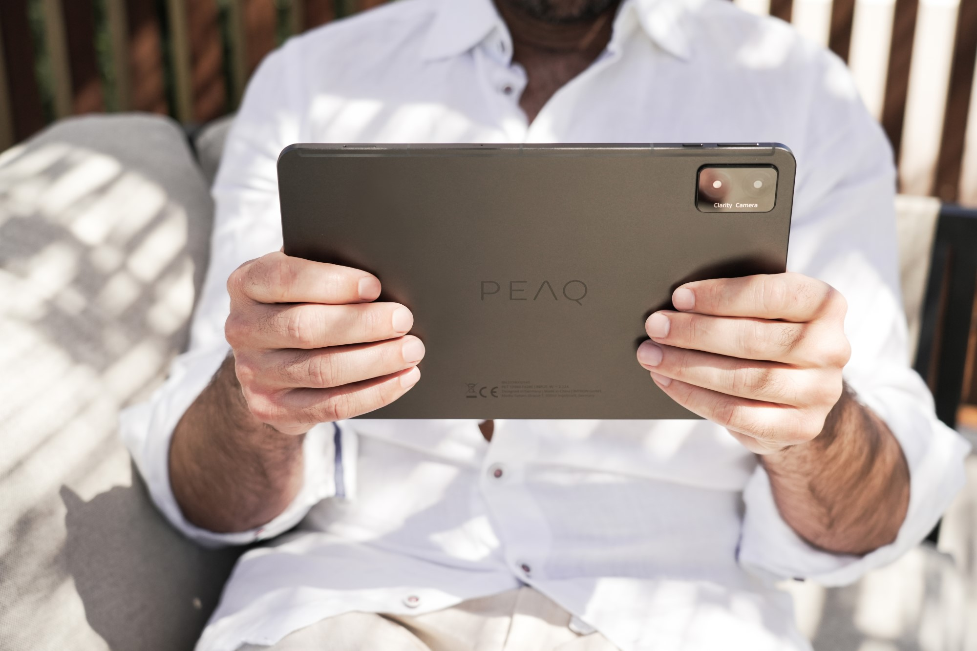 Mężczyzna w białej koszuli trzymający tablet, pokazujący tył urządzenia z logo marki.