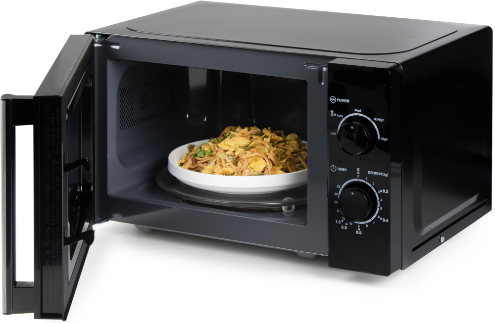 Four à micro-ondes noir avec la porte ouverte, une assiette de nourriture est à l'intérieur.