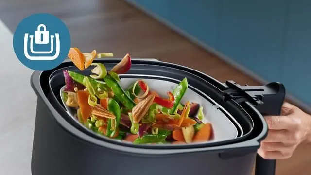 Koszyk do frytownicy powietrznej z warzywami umieszczanymi w środku, z widoczną ikoną blokady.