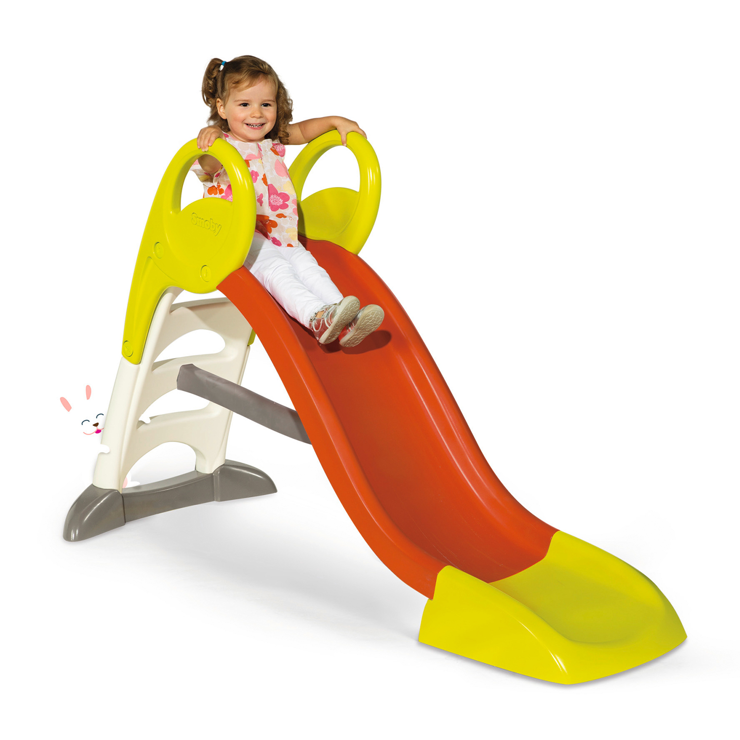 Una bambina che scivola giù da uno scivolo di plastica colorato su uno sfondo bianco.