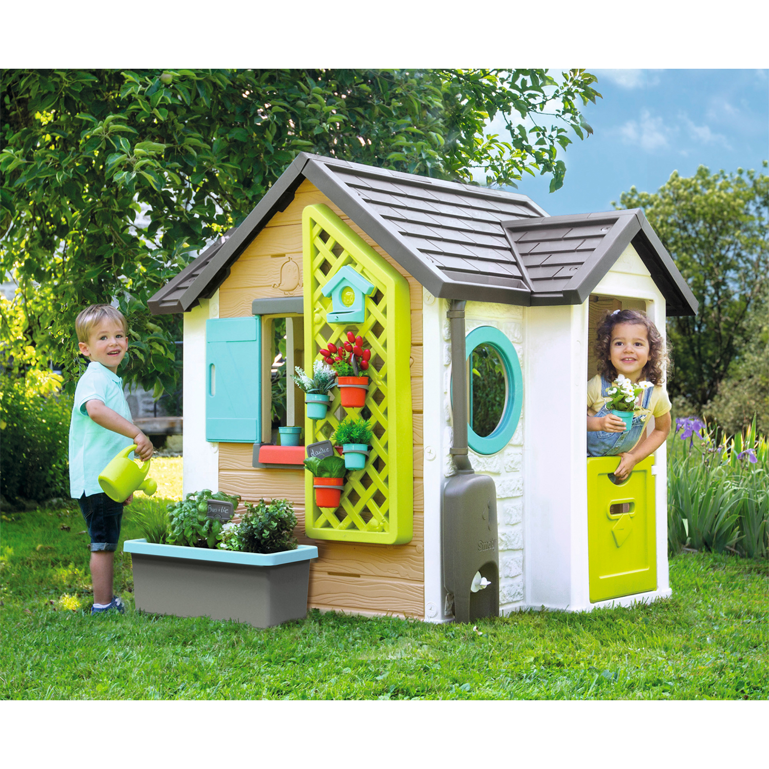 Bambini che giocano in una casetta. Erba verde e alberi sullo sfondo.