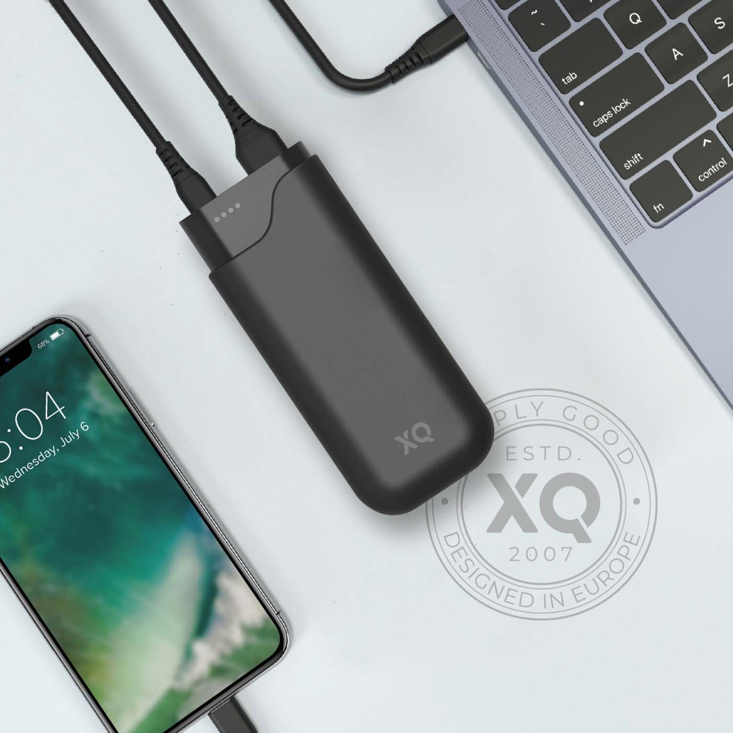 Un téléphone et un ordinateur portable se chargeant d'une batterie externe noire sur une surface blanche.