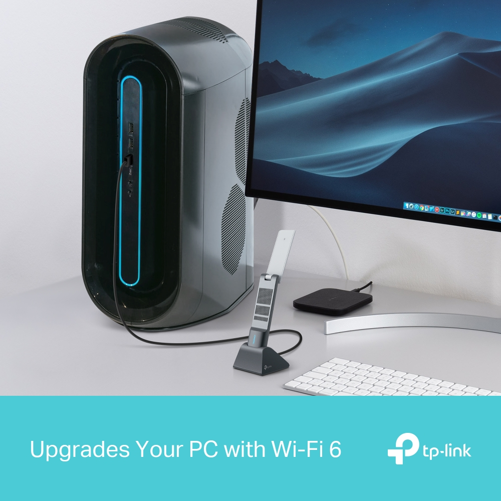 Mavi ışıklı siyah bir bilgisayar kasası, bir monitörün yanında. Ön planda bir Wi-Fi adaptörü.