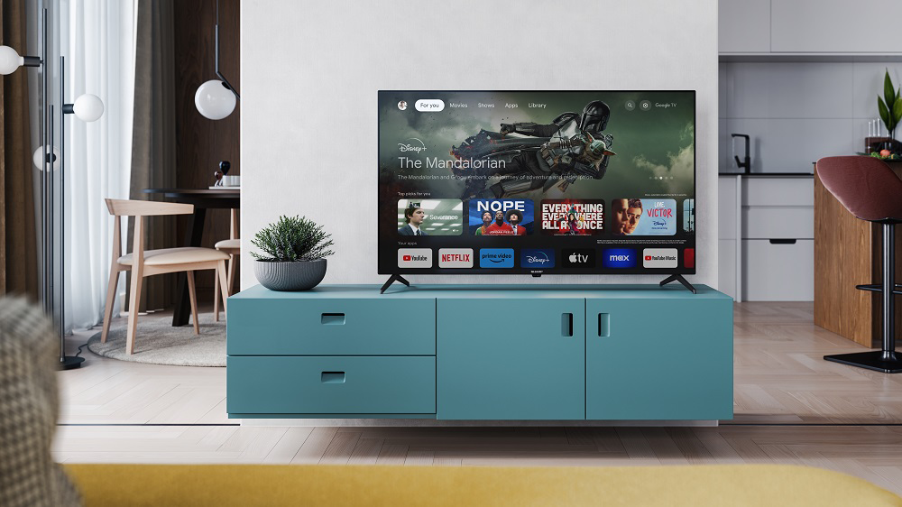TV műsort jelenít meg. Egy türkiz szekrény alatta. Modern nappali.