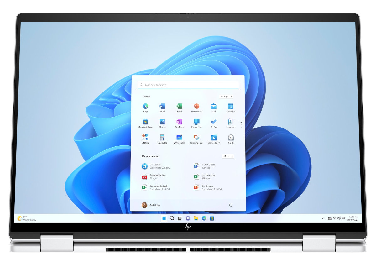 Srebrny laptop wyświetlający menu start Windows 11 na białym tle.