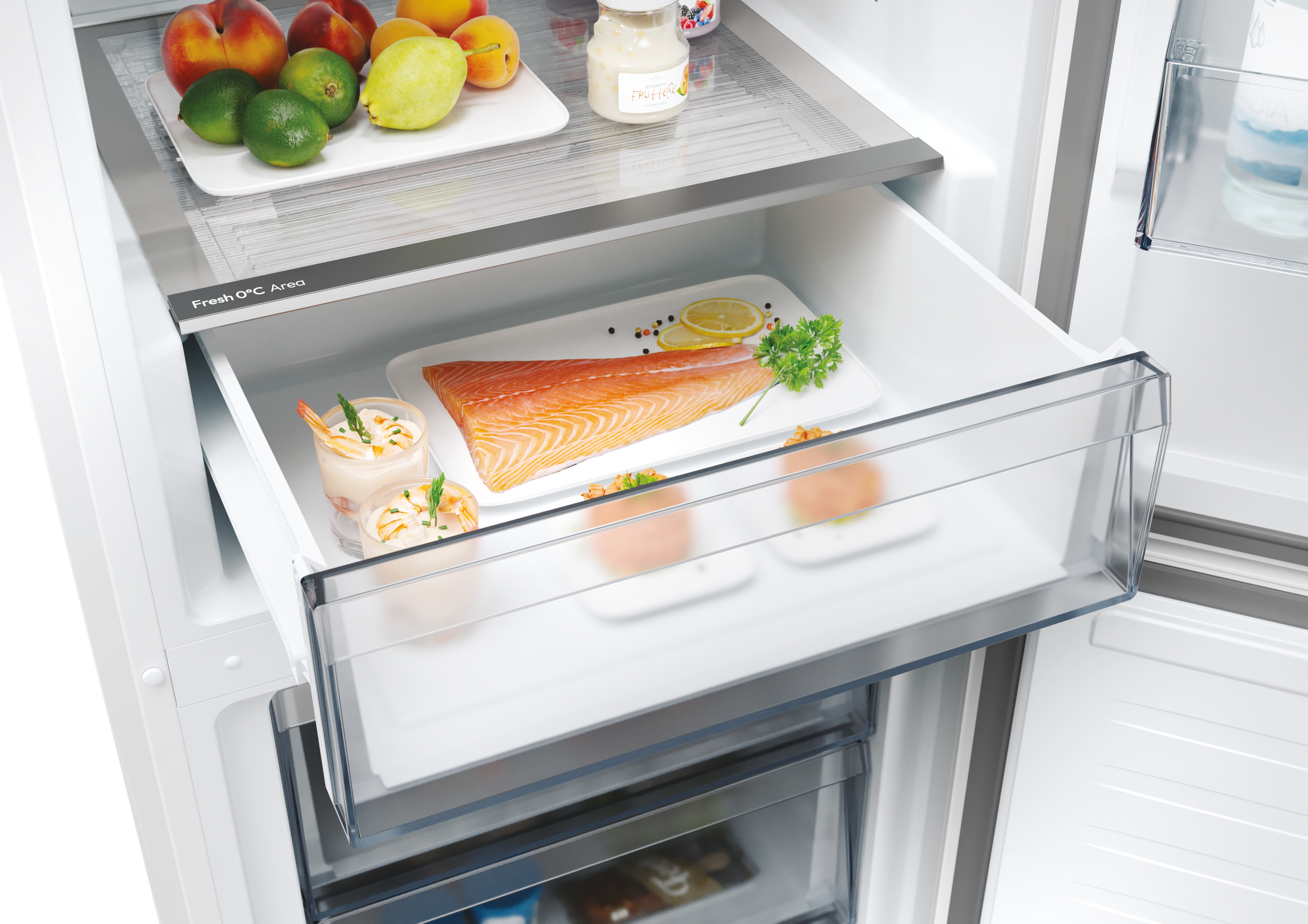 Un cajón de refrigerador con alimentos. Salmón, camarones y frutas son visibles.
