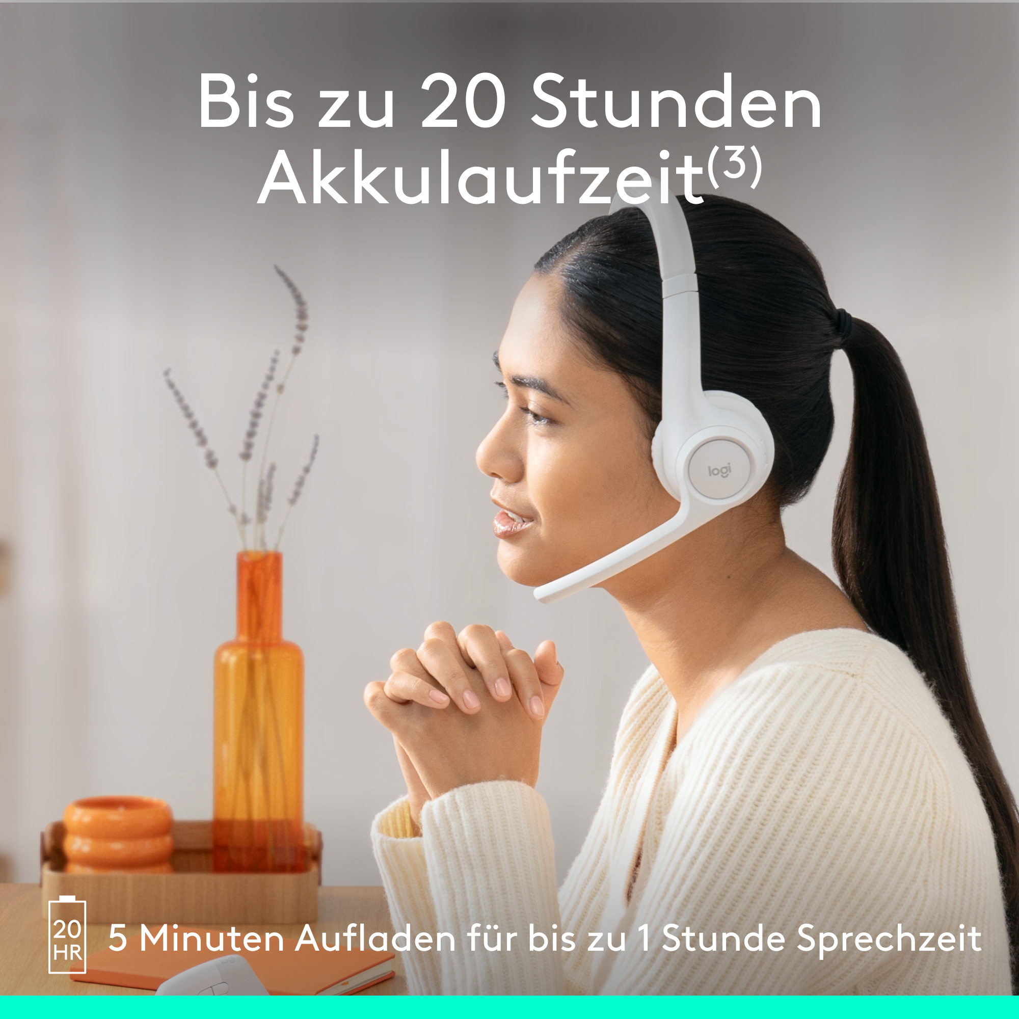 Eine Frau mit weißem Headset lächelt, mit Blumen und einem kleinen orangefarbenen Dekor im Hintergrund.