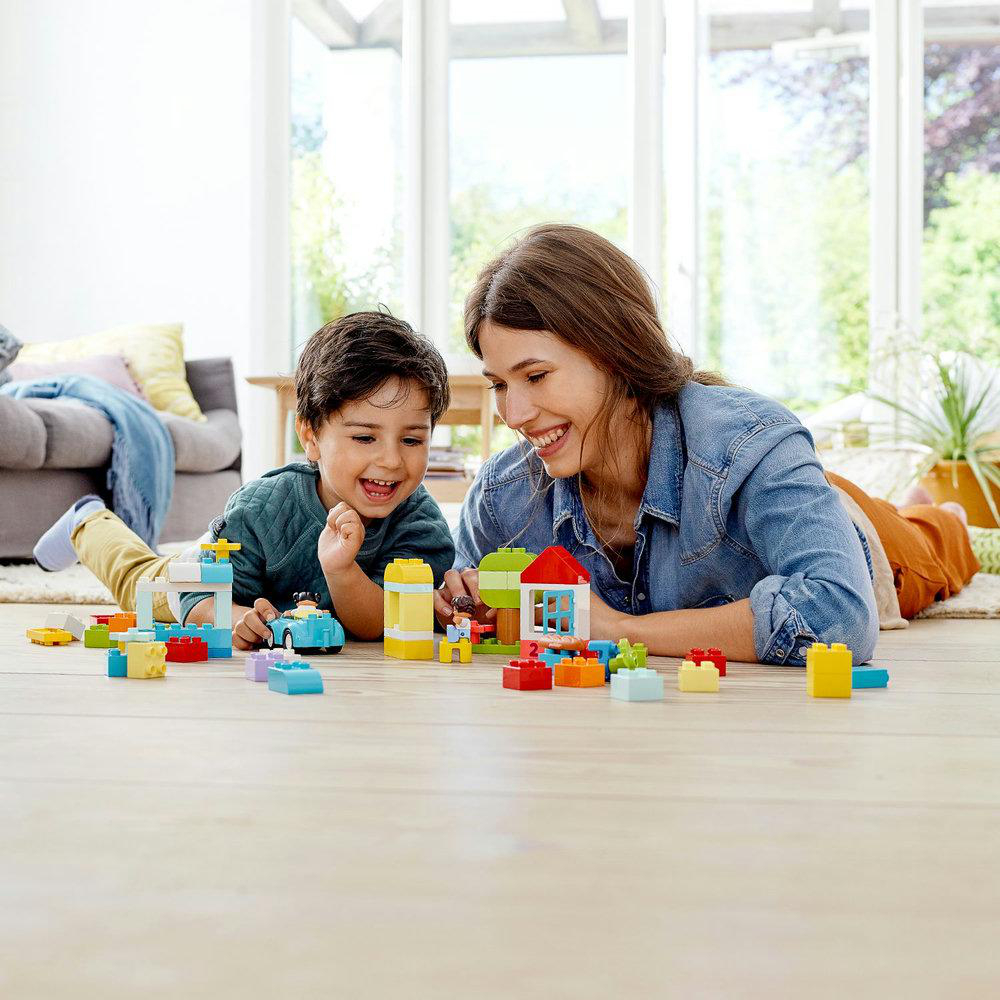 Mutter und Sohn spielen mit bunten Bausteinen auf dem Boden.