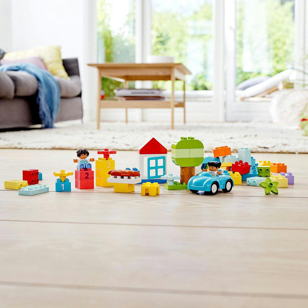 Spielzeugblöcke: Auto, Haus, Baum, Figuren, Zahlen 1-3 auf Holzboden.