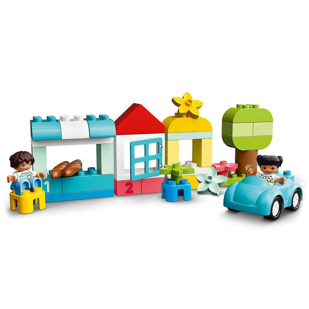 Lego-Spielzeug: Kinder, Häuser, ein Auto, ein Baum und Blumen auf weißem Hintergrund.