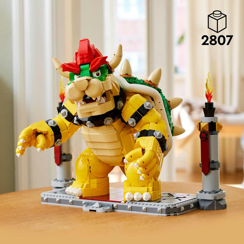 Lego Bowser-Figur mit roter und grüner Stachelpanzerung, steht auf grauer Basis mit Fackeln.