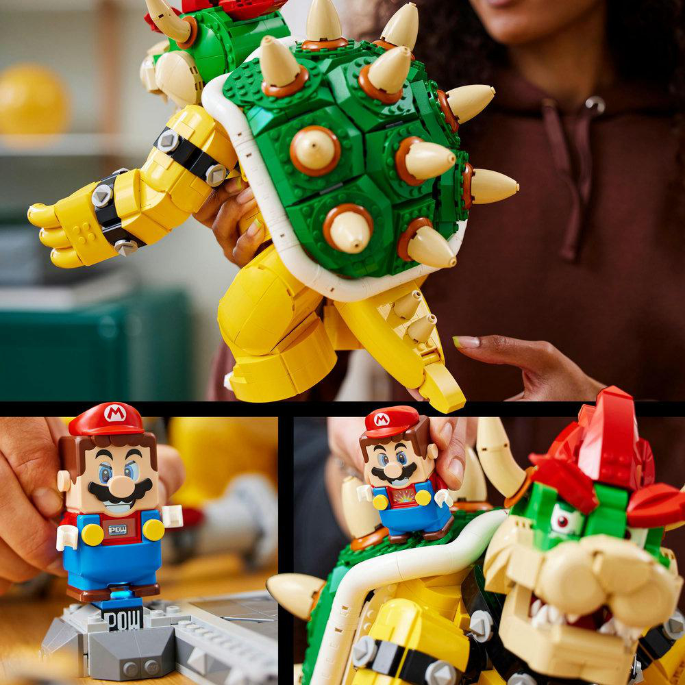 Lego Bowser Spielfigur mit Lego Mario und einem Block, mit einer Hand im Bild.