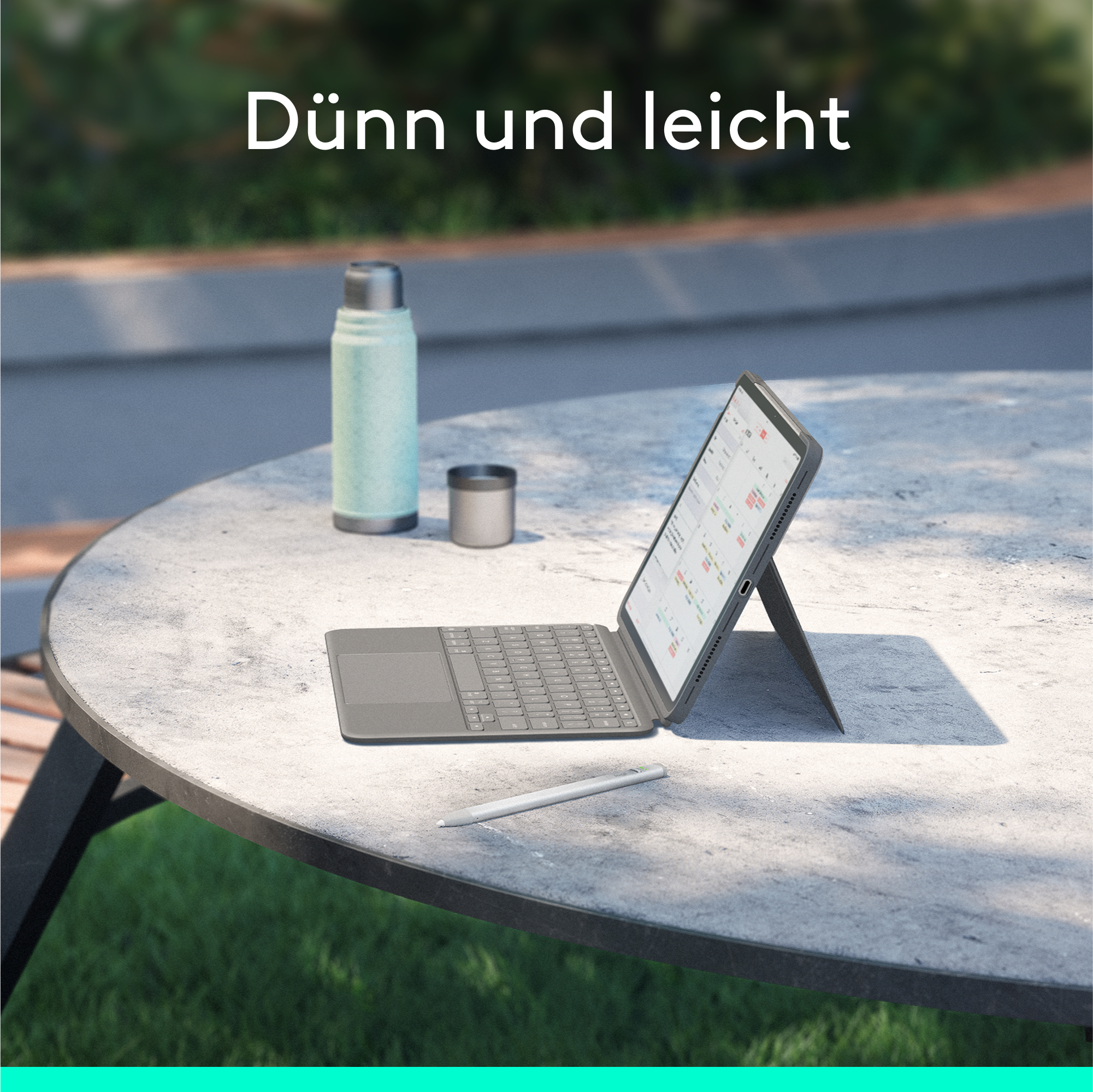 Tablet mit Tastatur auf Tisch, mit Wasserflasche, Stift und Becher.