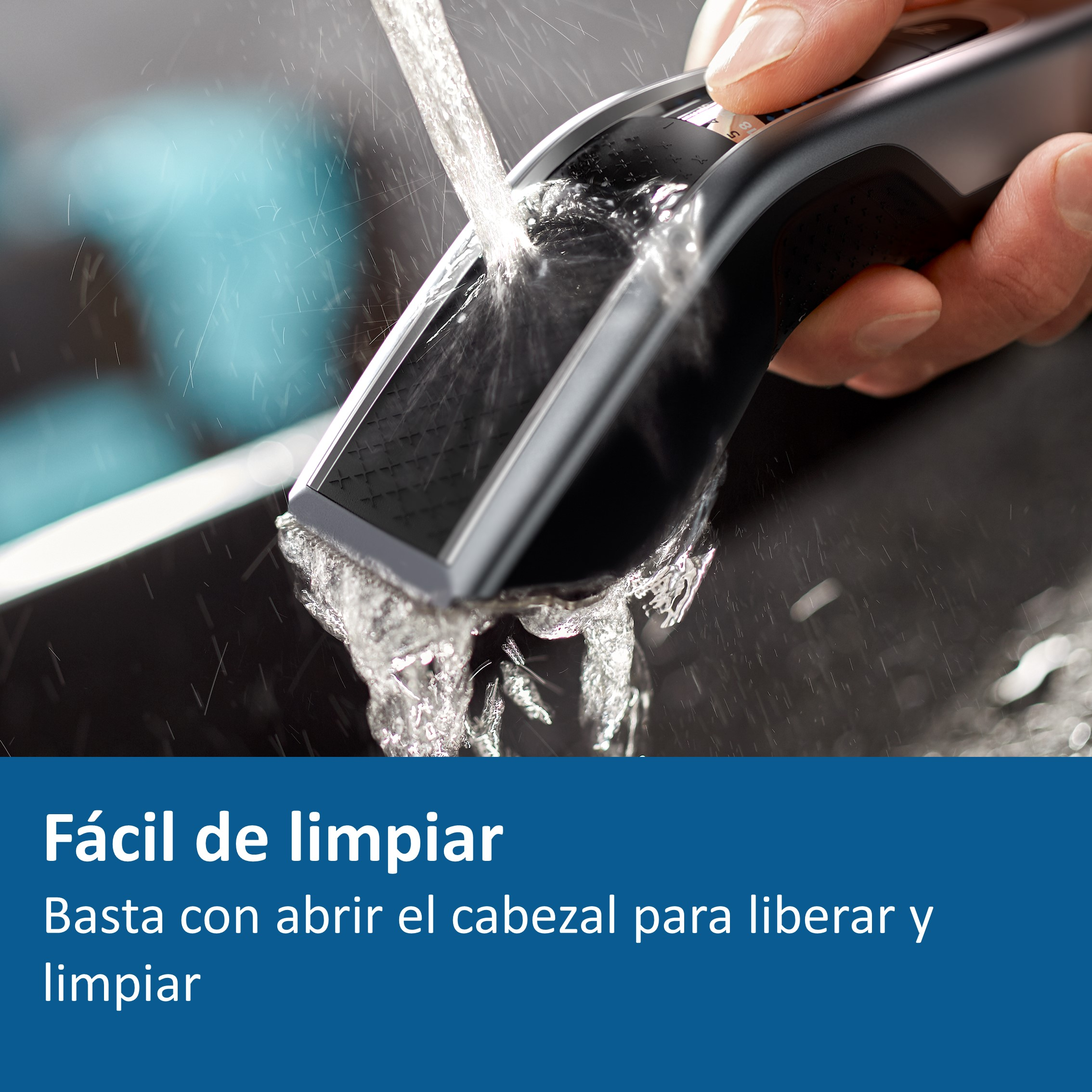Primer plano de una cortadora de cabello negra que se lava con agua, mostrando una mano que la sostiene.