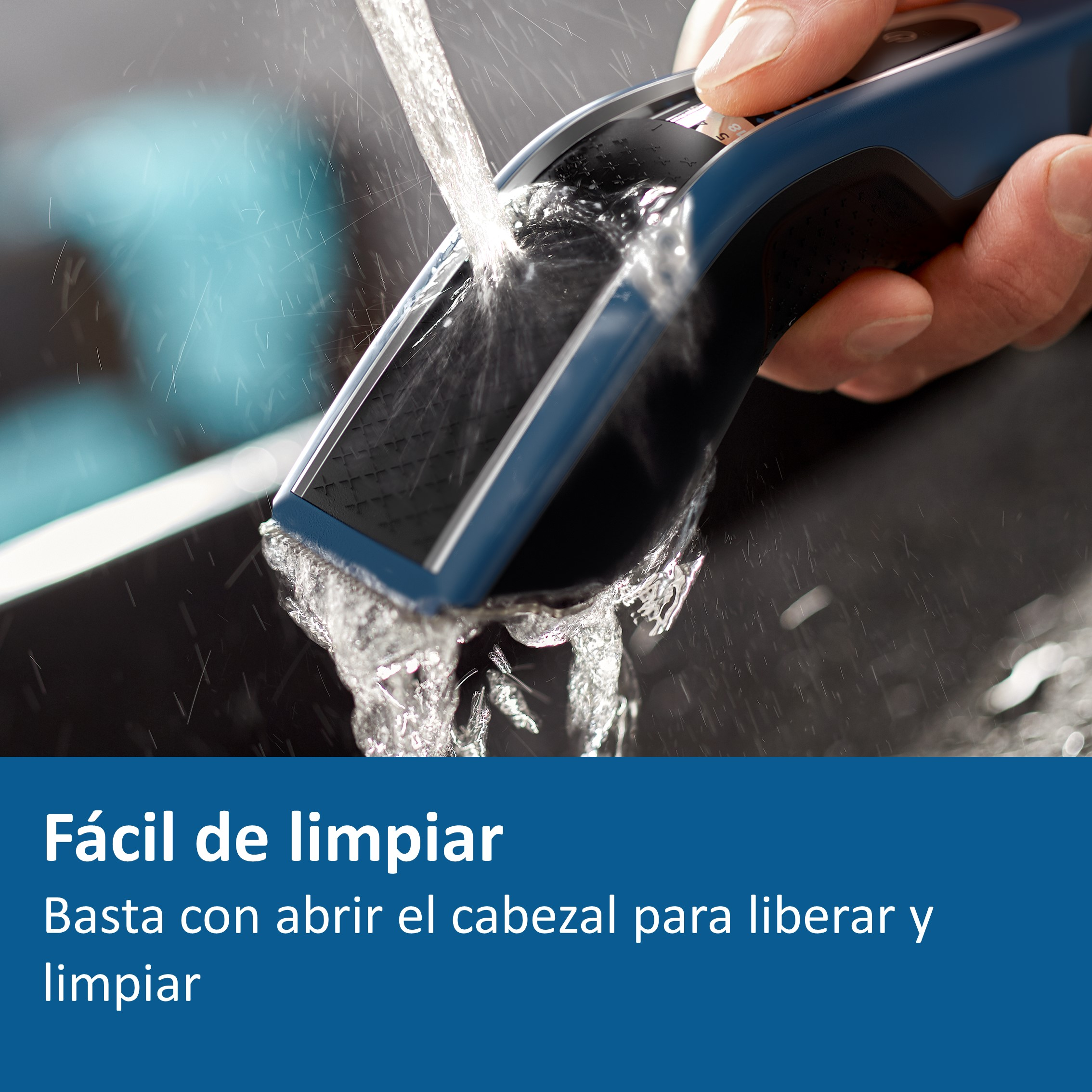 Una persona limpiando una afeitadora eléctrica azul con agua, primer plano, sobre una superficie negra.