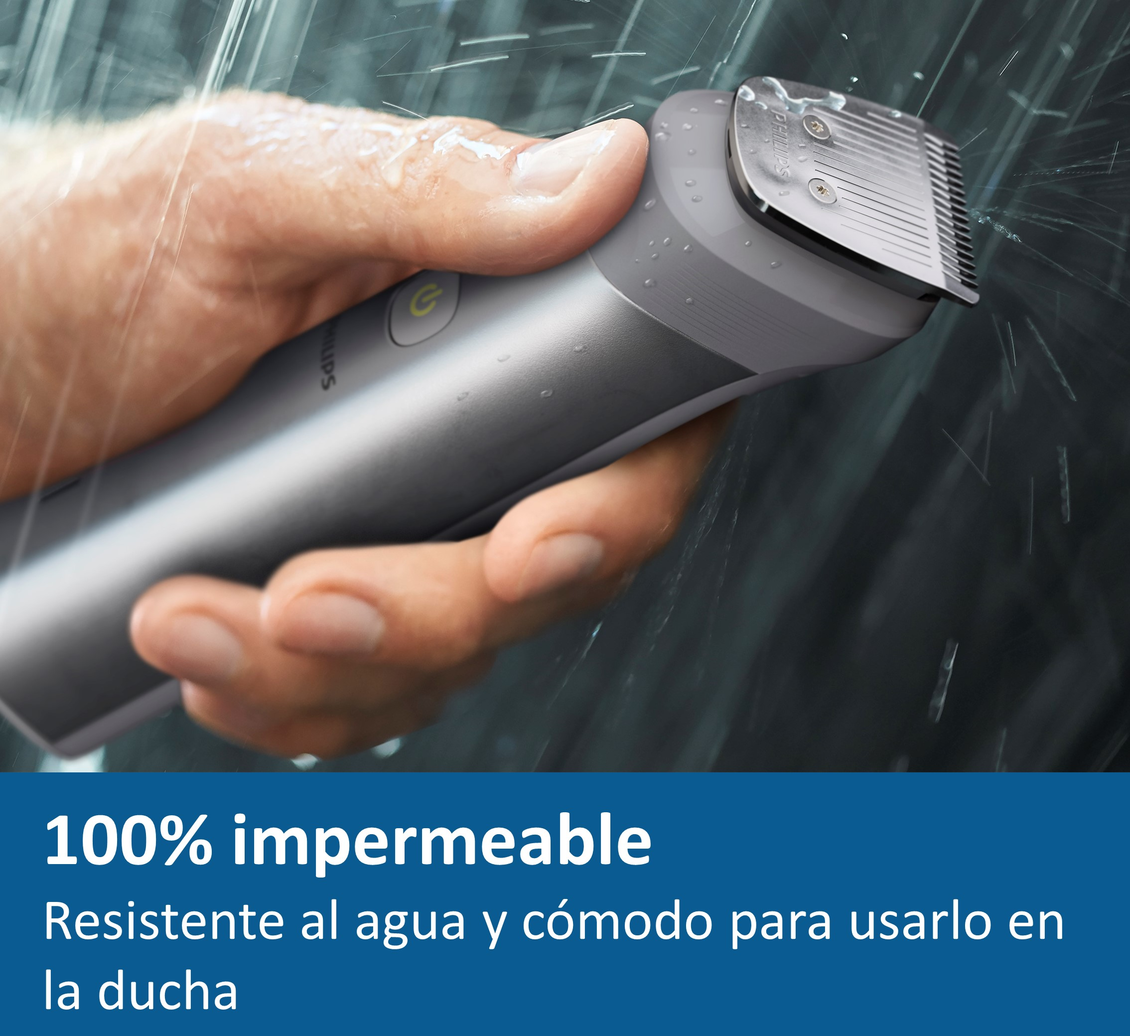 Mano sosteniendo un recortador impermeable plateado y gris con gotas de agua, en ducha.