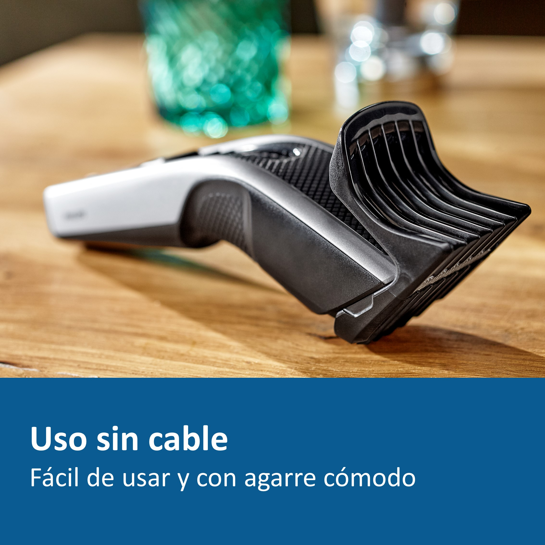 Una recortadora de pelo negra y plateada sobre una mesa de madera, con texto 'Uso sin cable'.