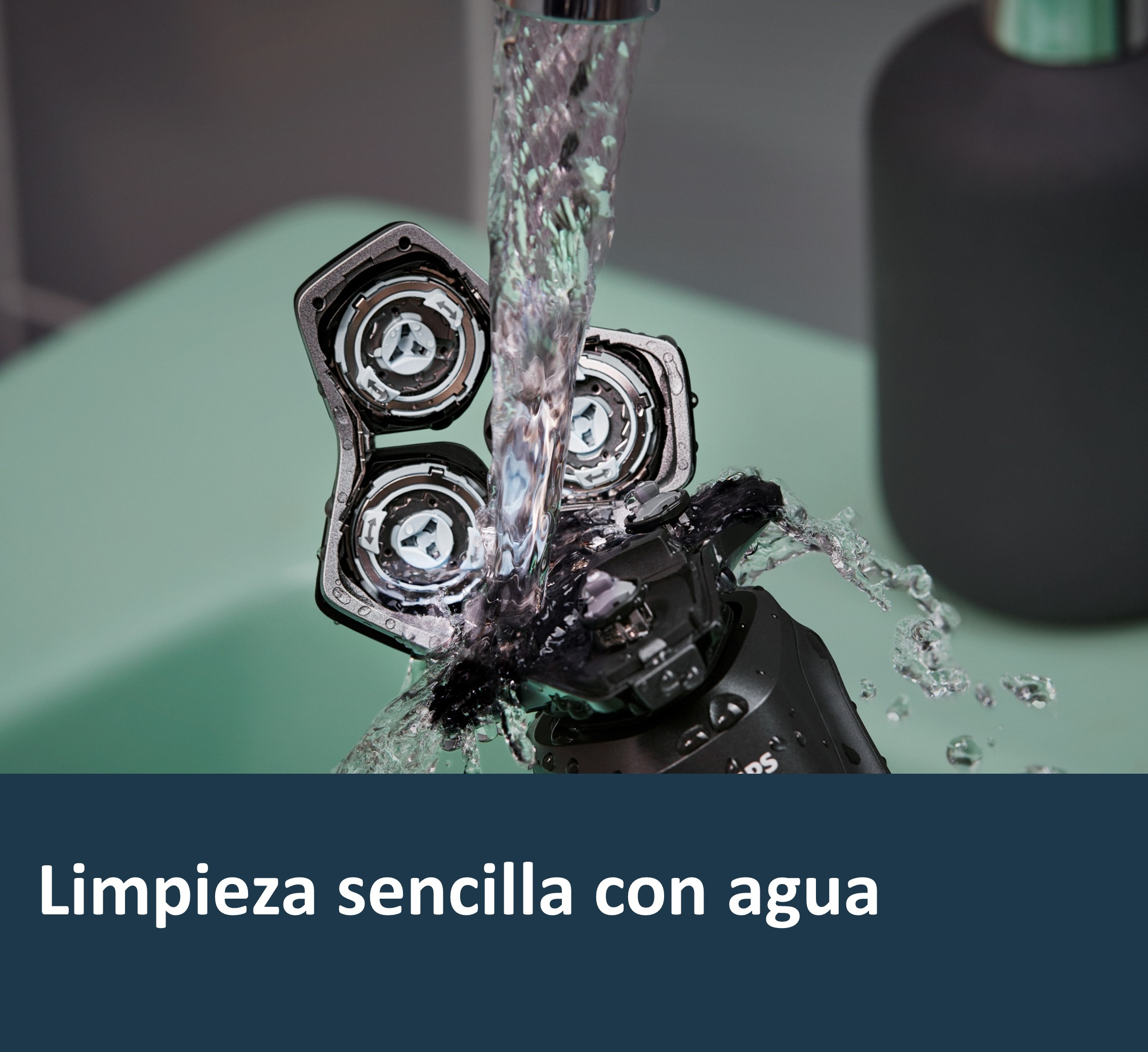 Afeitadora eléctrica bajo agua corriente, con tres cabezales rotatorios visibles, sobre fondo verde claro.