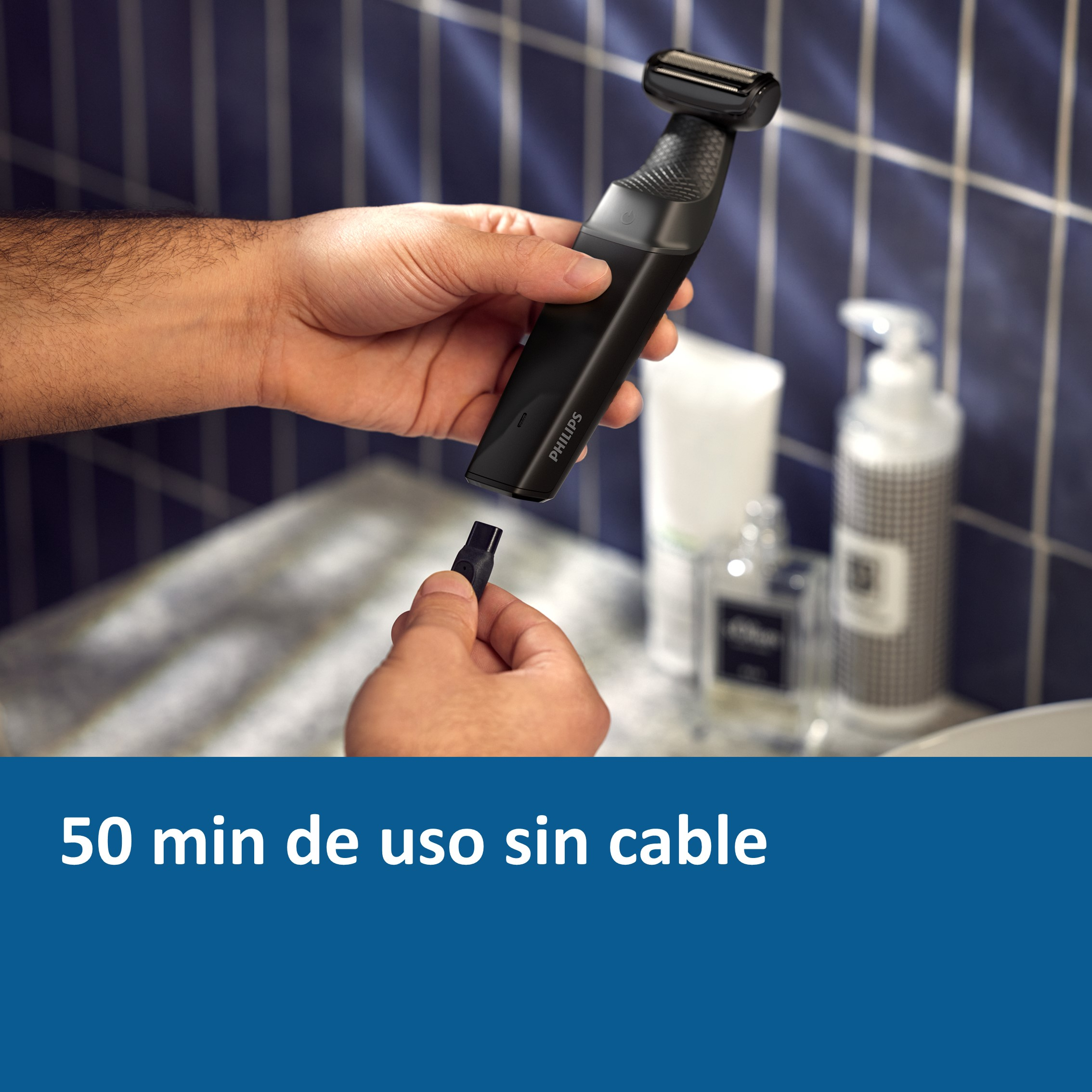 Una persona sostiene una afeitadora negra cerca de un lavabo, texto: 50 min de uso sin cable.