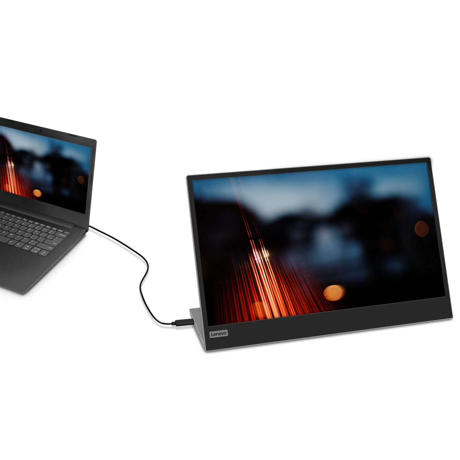 Laptop connected to a portable monitor. Background is a blurred cityscape.