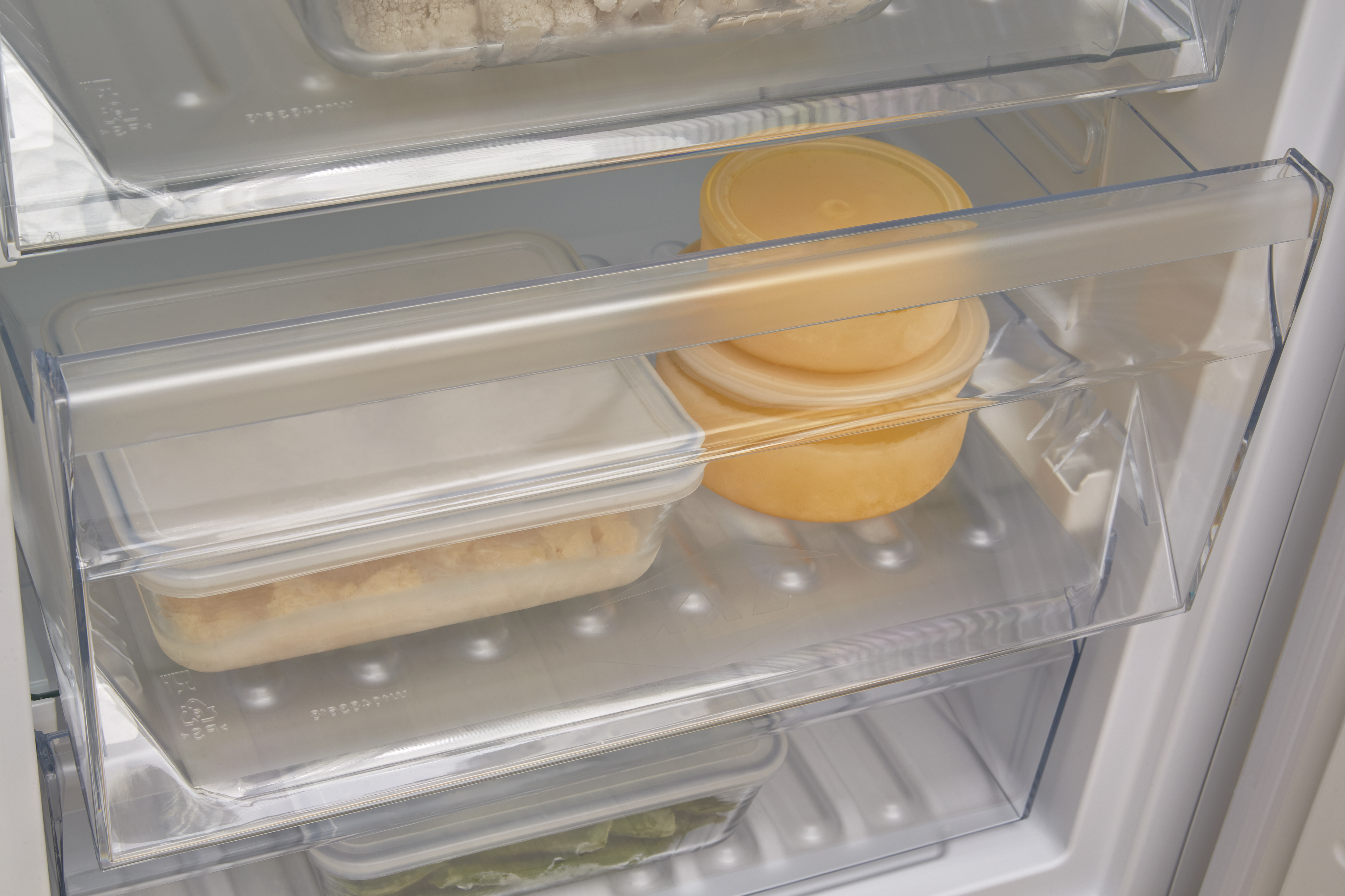 Un refrigerador abierto con recipientes transparentes de comida en los estantes.