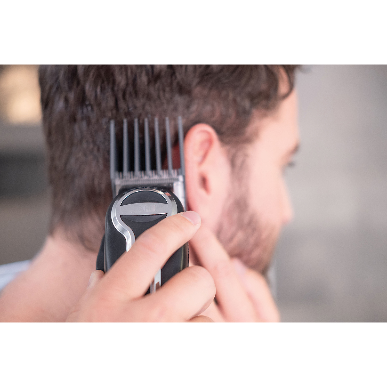 Una persona usa un tagliacapelli sui capelli di un'altra persona, primo piano dell'azione.