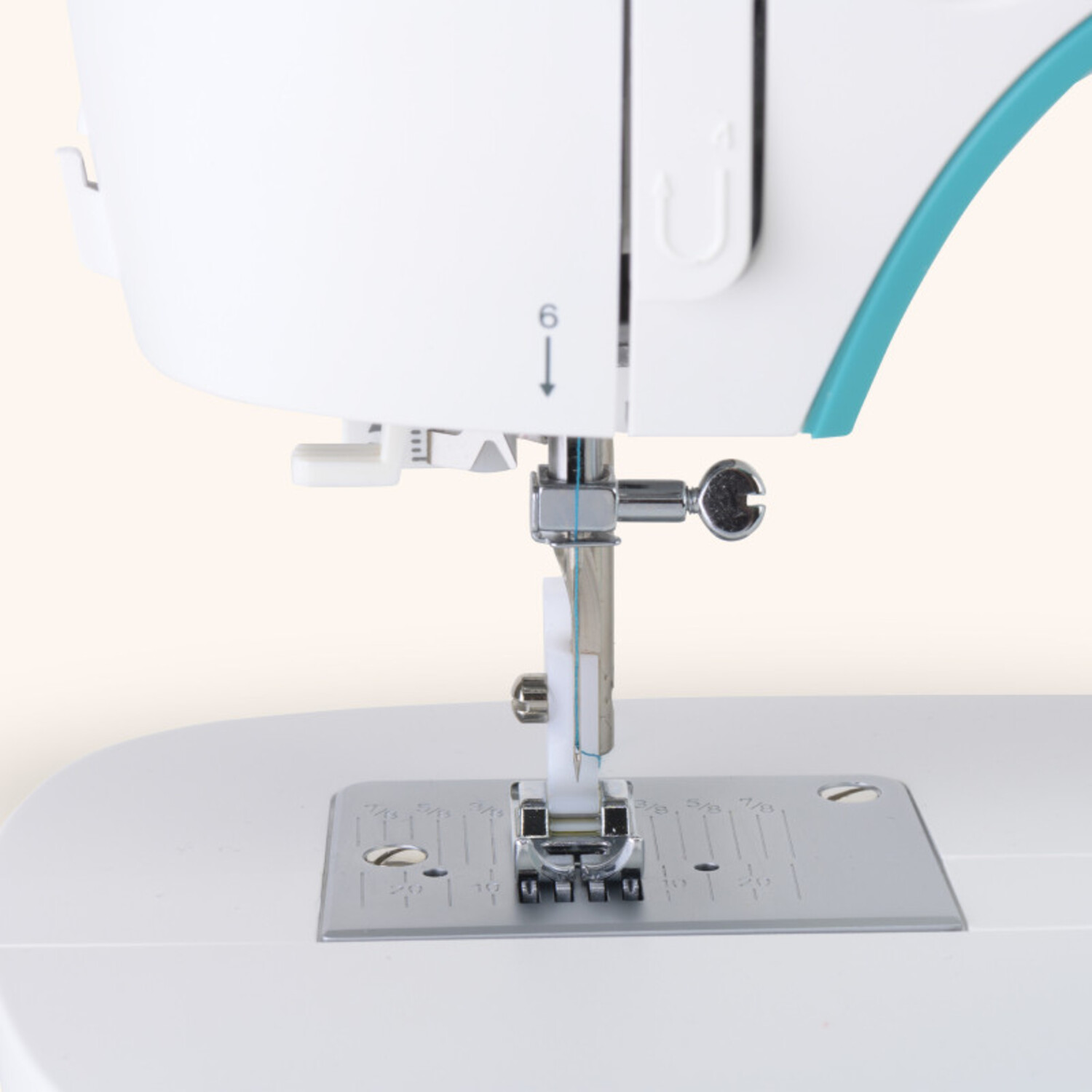 Machine à coudre, aiguille et pied, gros plan sur fond beige clair.