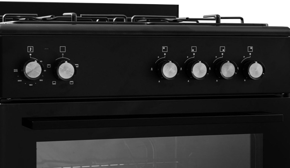 Black oven with knobs. Close-up view. Knobs show settings for cooking. Black oven door below. 