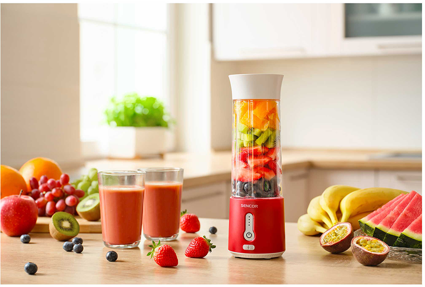 Turmixgép vegyes gyümölcsökkel, két smoothie pohárral és különféle gyümölcsökkel a faasztalon.