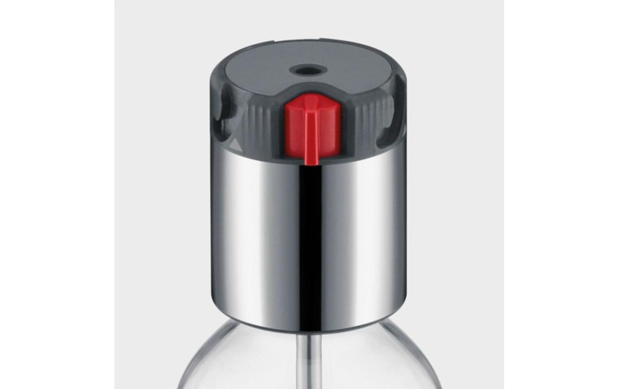 Nahaufnahme eines metallischen Flaschenverschlusses mit rotem Knopf oben.