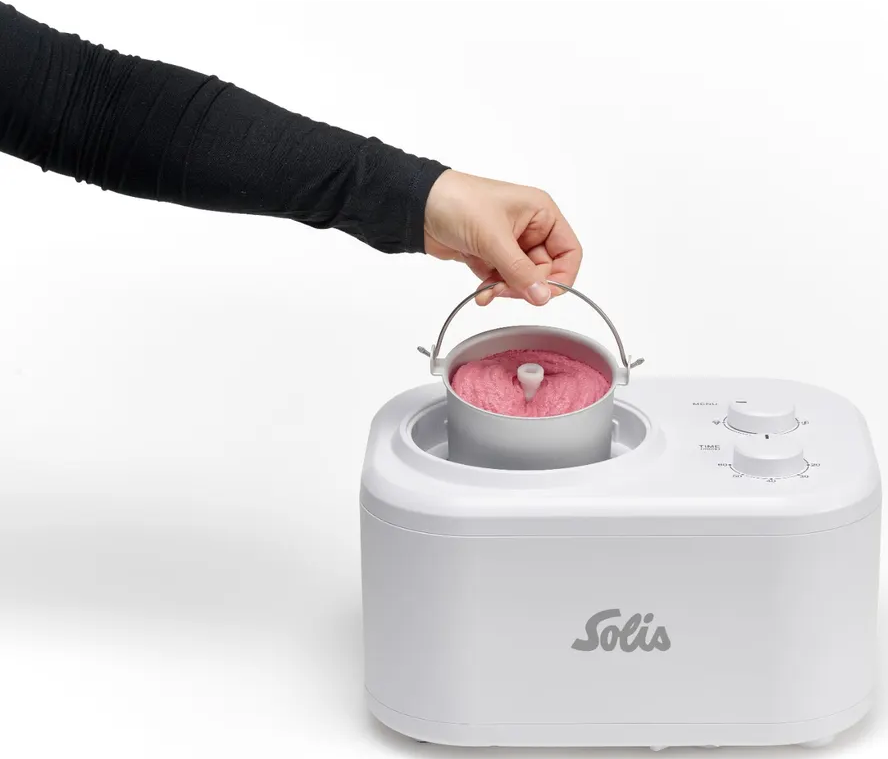 Person hält silbernen Behälter mit rosa Eis, weißer Eismaschine mit Solis-Logo.