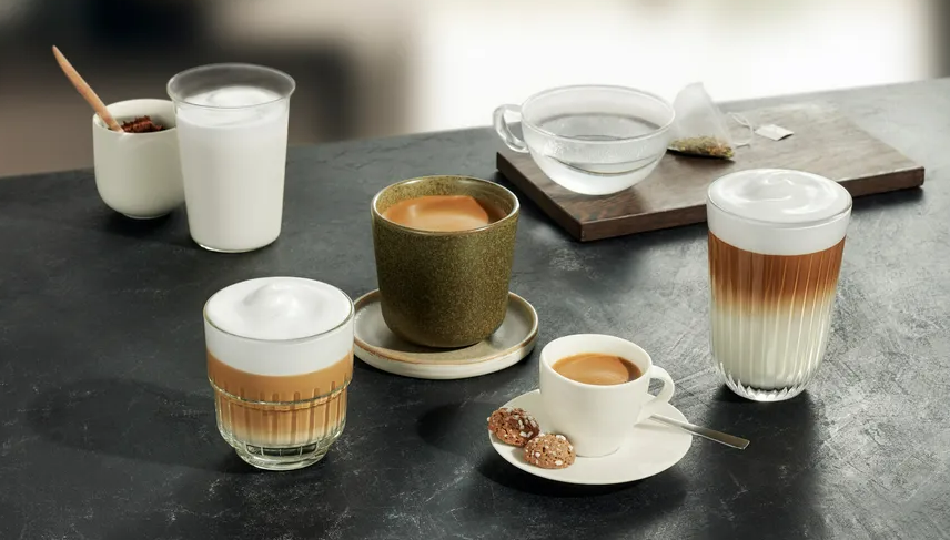 Verschiedene Kaffeegetränke auf dunkler Oberfläche: Latte, Espresso und Tee. Zutaten in der Nähe.