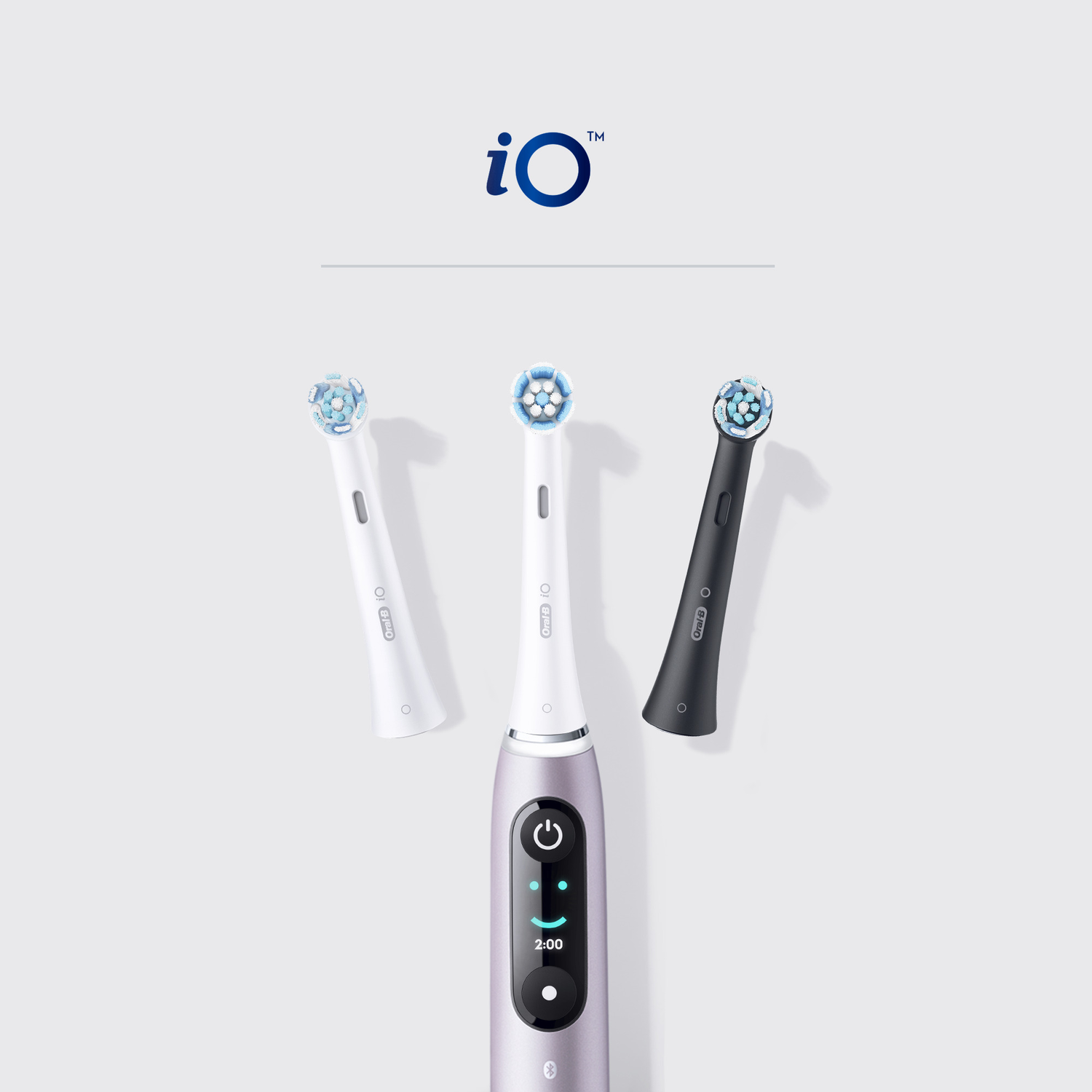 Oral-B iO electric toothbrush and three brush heads. Two white and one black.