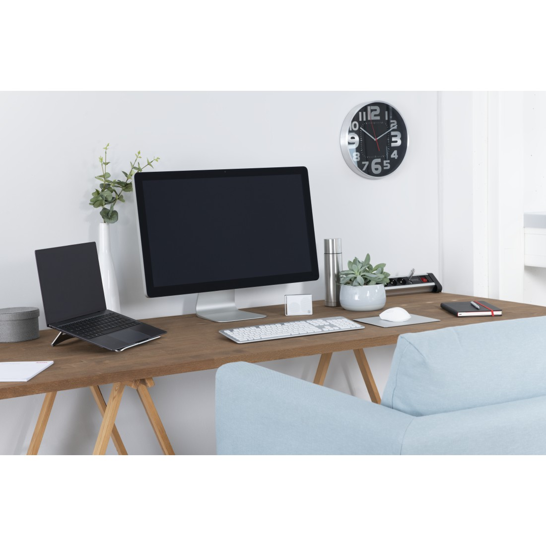 Espacio de trabajo con portátil, monitor, teclado, ratón y un reloj en la pared.