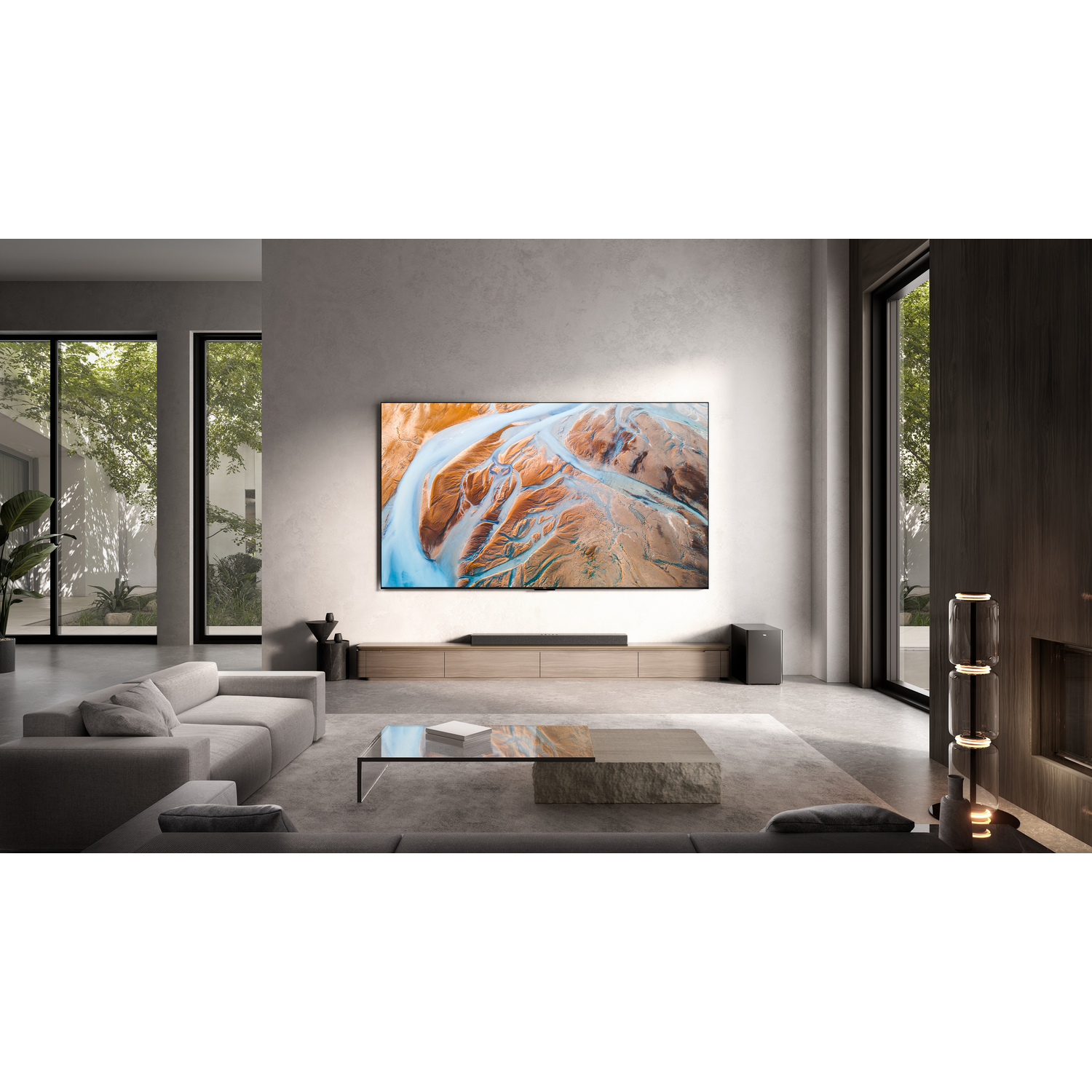 Een moderne woonkamer met een grote tv die een landschapsafbeelding weergeeft. Neutrale kleuren, ramen en een bank zijn aanwezig.