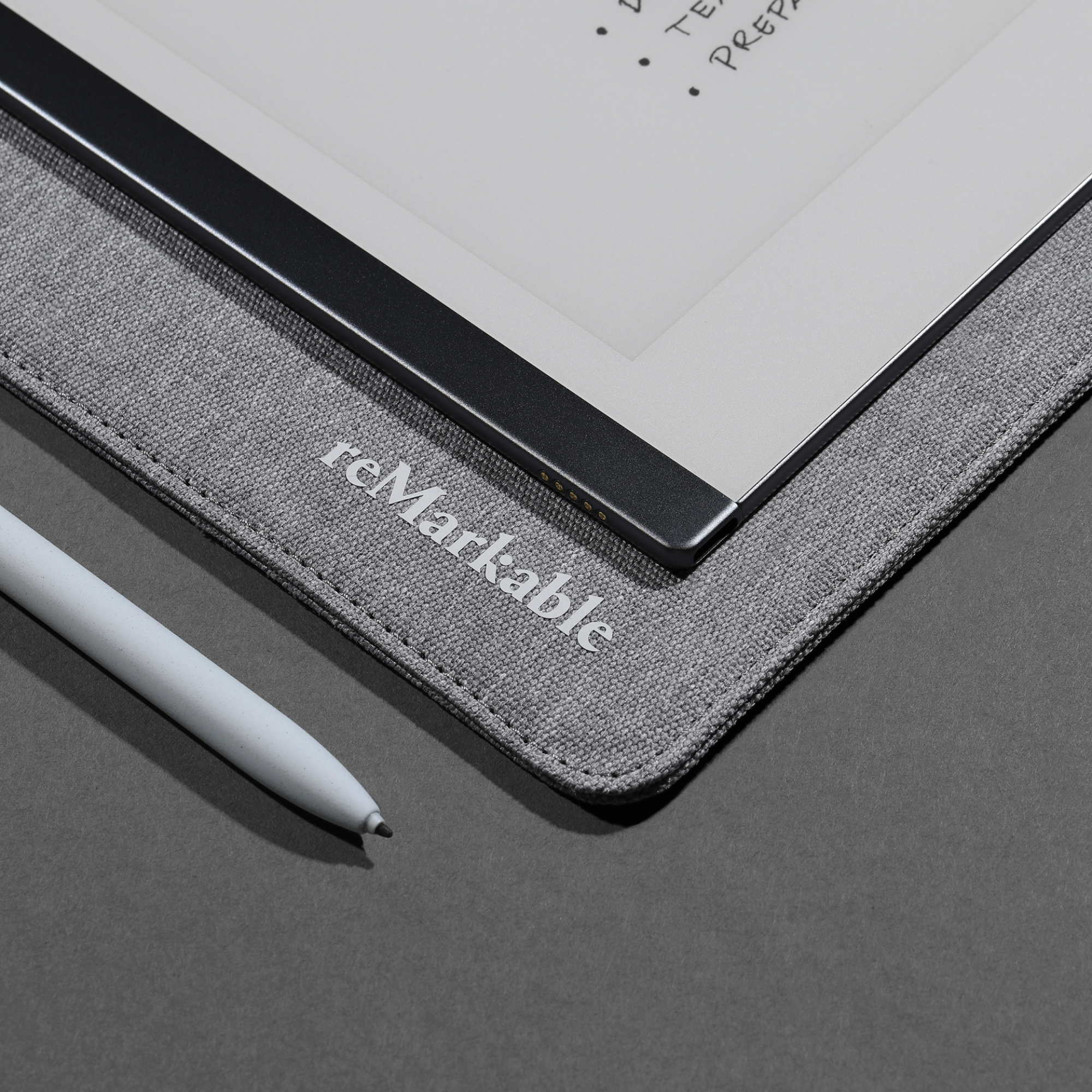 Eine bemerkenswerte graue Hülle und ein Stift auf dunkler Oberfläche. Text: reMarkable.