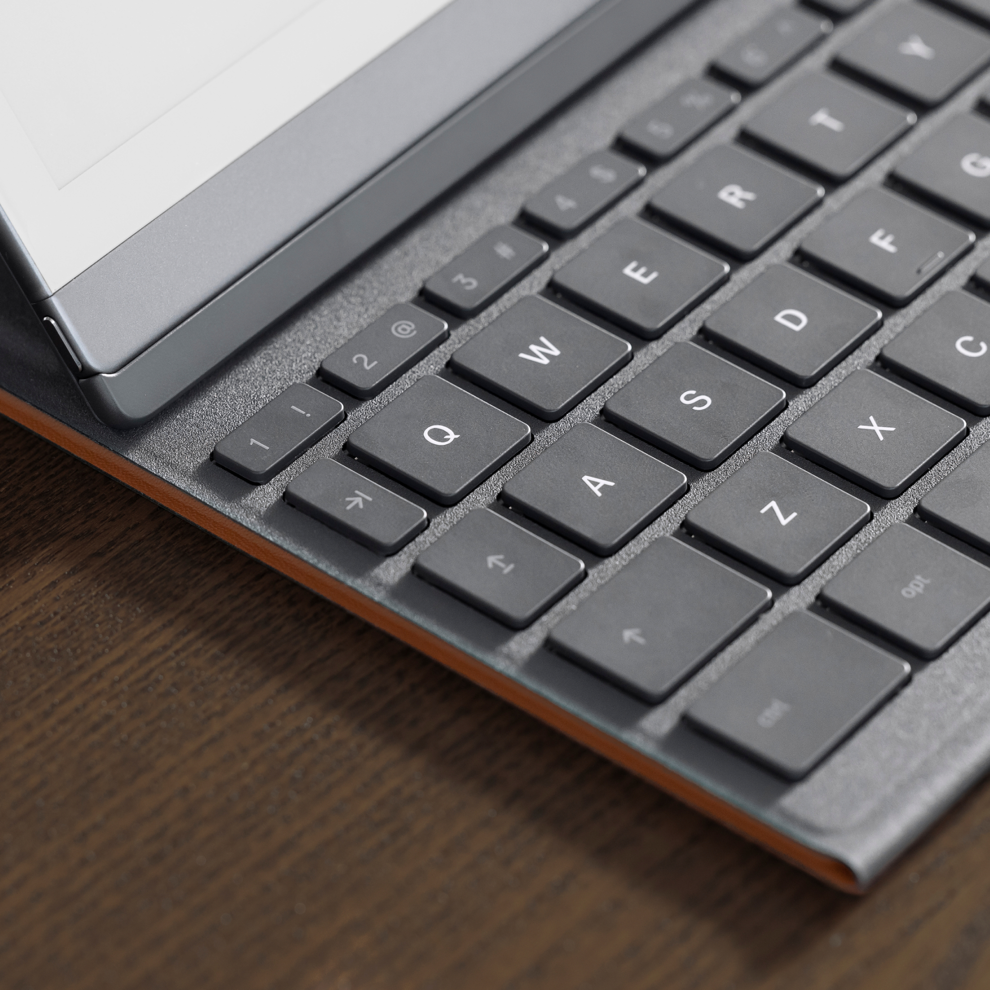 Nahaufnahme einer Tastatur mit grauen Tasten und einem Tablet. Die Tastatur hat eine holzähnliche Textur.