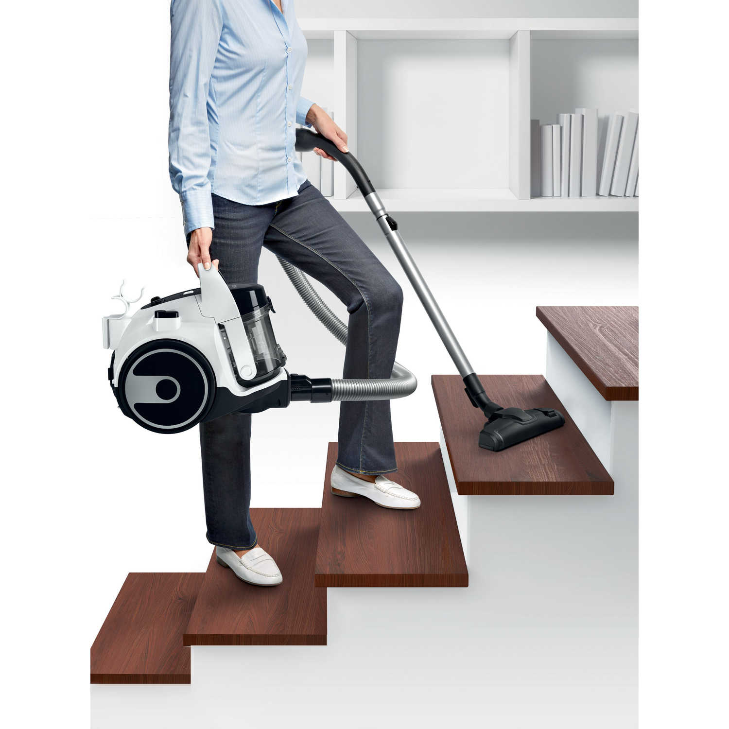 A woman vacuums stairs with a vacuum cleaner.