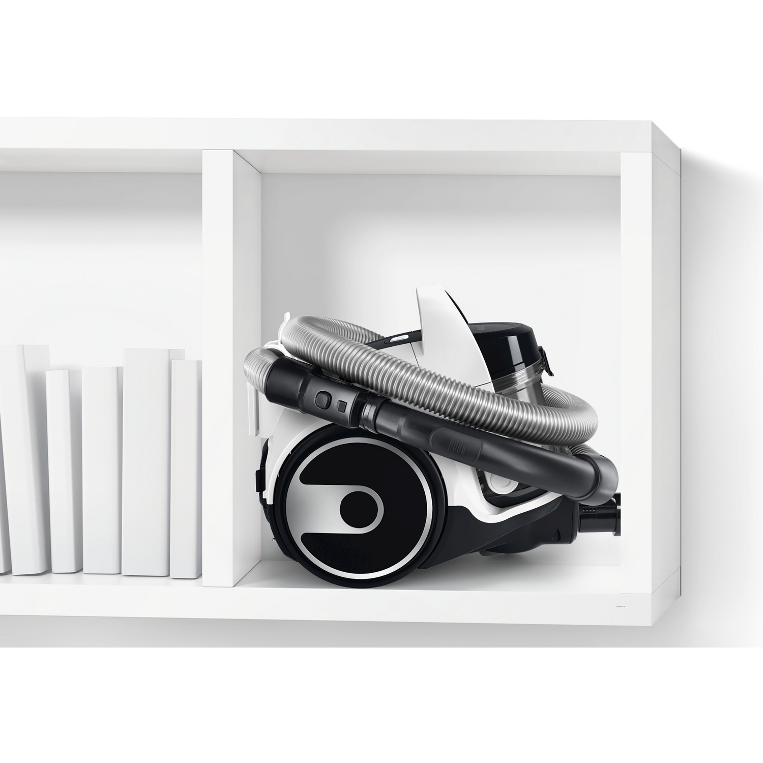 A white and black vacuum cleaner is stored in a white shelf unit.
