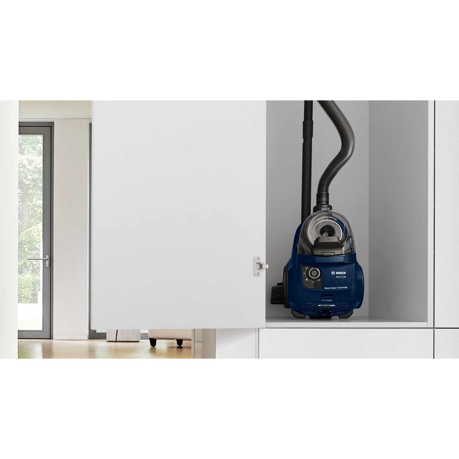 A blue vacuum cleaner is stored in a white cabinet. The door is open.